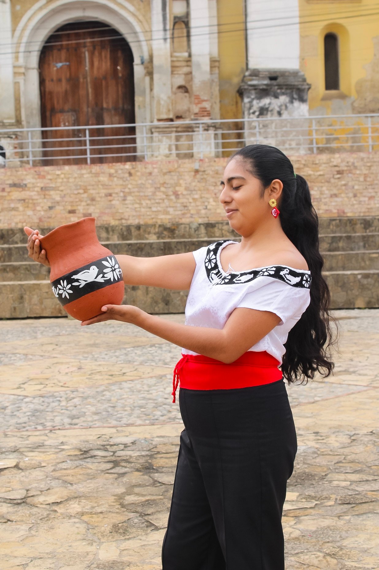 mujer zoque mostrando la alfareria pintada a mano con decarocion zoque